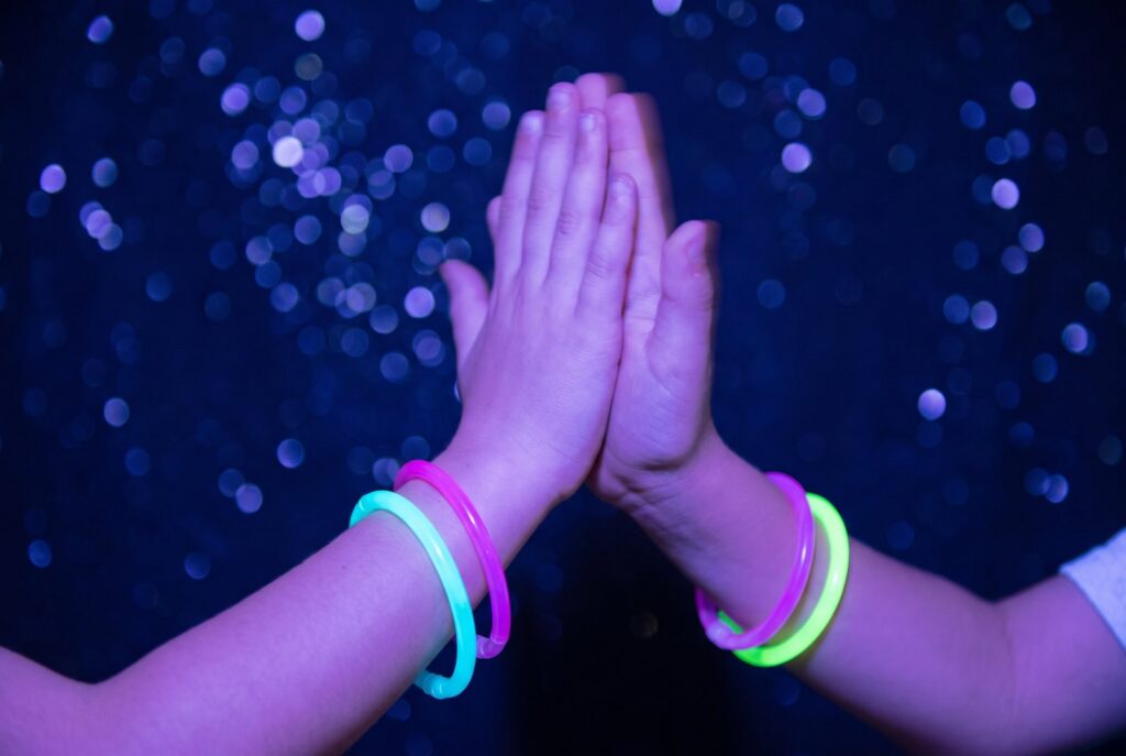 Zwei Kinder geben sich ein High five mit leuchtenden Armbändern