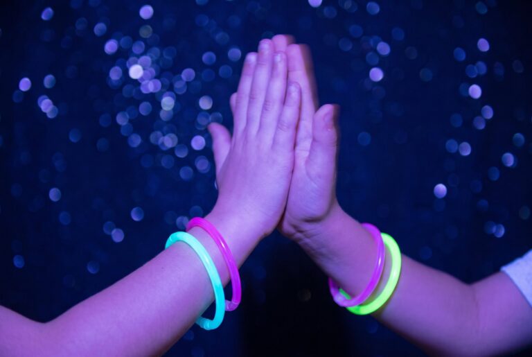 Zwei Kinder geben sich ein High five mit leuchtenden Armbändern