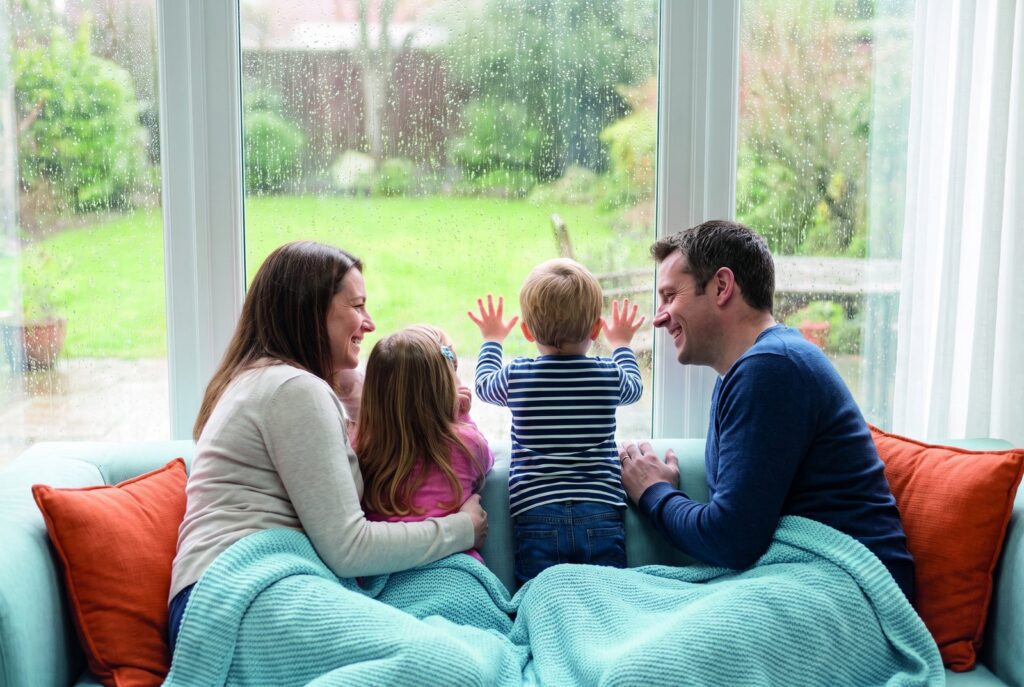 Familie schaut aus dem Fenster in den Sommerregen