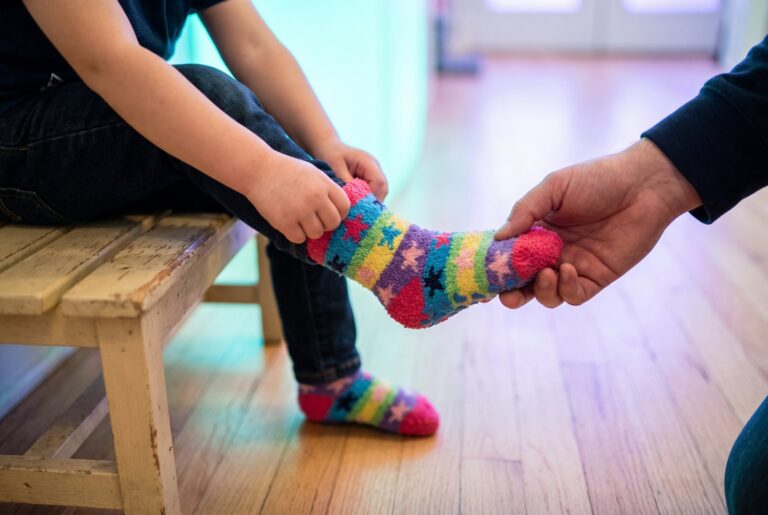 Kind zieht bunte Stoppersocken mit Sternen an