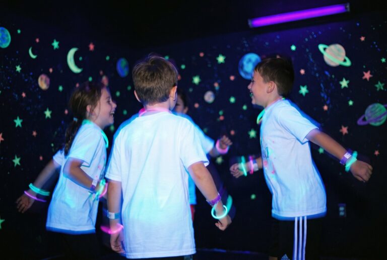 Kinder tanzen im UV-Licht mit leuchtenden T-Shirts